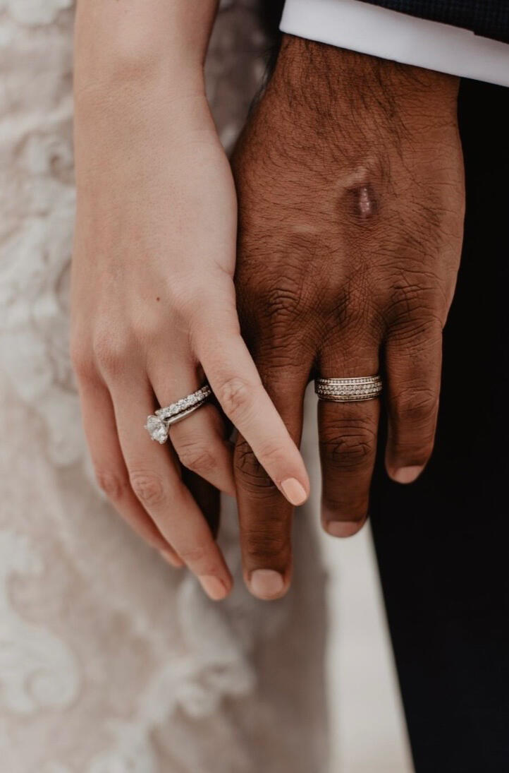 Zwei Hände mit Trauringen halten sich